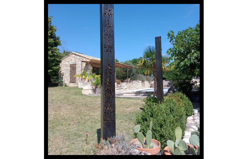 Poteau métallique en découpe plasma dans un jardin, réalisé par Fabien Lovisa.